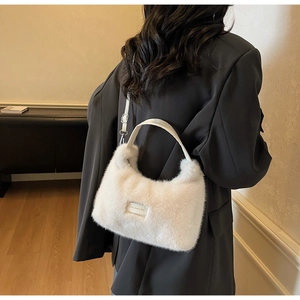 Detail view of a white plush faux fur crossbody bag with leather handle and metal buckle