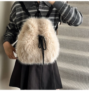 Detail of beige faux fur backpack with black drawstring and adjustable straps on a model