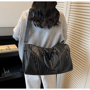 Détail du sac de voyage noir tissé avec poignées et bandoulière amovible réglable