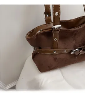 Gros plan d'un sac cabas en daim marron avec boucles argentées et coutures blanches