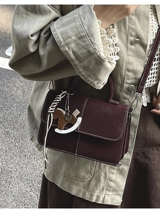 Chic burgundy square crossbody bag with white stitching and rocking horse charm detail