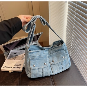 Détail d'un sac en denim délavé bleu clair avec poches cargo sur un banc en cuir marron