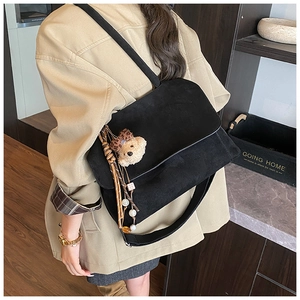 Close-up of black frosted tote bag with cute bear charm and tassel detail on shoulder