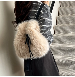 Detail view of a beige faux fur drawstring backpack with black straps on a female model