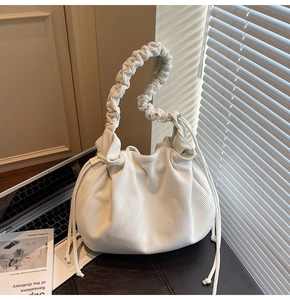 Detailansicht einer cremefarbenen Cord-Beuteltasche mit geflochtenem Griff und Kordelzug