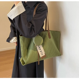 Grass green quilted tote bag with brown straps and mini pouch worn on shoulder