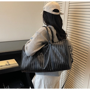 Vue latérale du grand sac de voyage tressé noir avec bandoulière amovible et style épuré