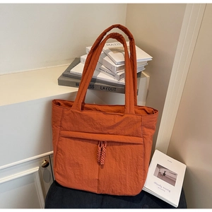 Detail der gesteppten Tragetasche in Orange mit gewebten Quasten und weicher Nylonstruktur