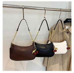 Détail de trois sacs hobo en cuir texturé avec chaînes dorées et pendentifs cerises