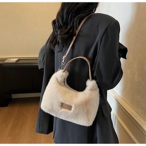 Detailed view of plush beige faux fur shoulder bag with leather straps on a model