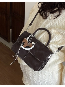 Brown vintage crossbody bag with white stitching and leather horse charm on model