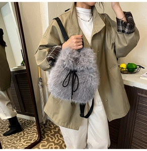 Detail view of a soft grey faux fur backpack with black drawstring and adjustable straps
