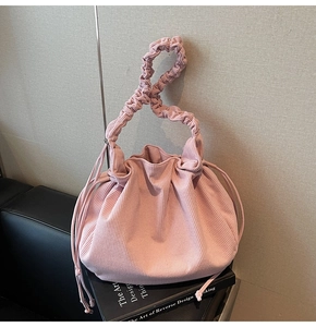 Nahaufnahme der hellrosa Cord-Handtasche mit Kordelzug und plissiertem Tragegriff