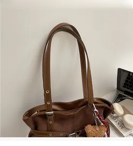 Détail du sac cabas en daim marron avec rivets métalliques et breloque ours en peluche