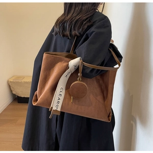 Close-up of brown suede tote bag with decorative CLEAR ribbon and mini coin purse