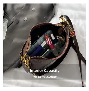 Vue intérieure d'un sac bandoulière en cuir marron avec chaîne et objets essentiels