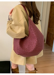 Close-up of wine red leopard print tote bag worn by a model in a retro setting
