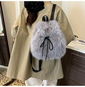Detail of grey faux fur backpack with black drawstring bow and soft plush texture