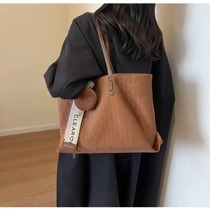 Detailed view of brown frosted tote bag featuring quilted stitching and a round coin pouch