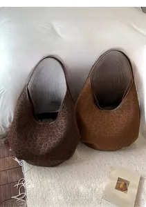 Macro detail of large leopard print hobo bags in brown and coffee faux suede texture