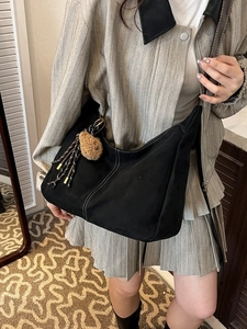 Grande borsa hobo in tela nera con cuciture bianche e ciondolo a forma di orso per il relax