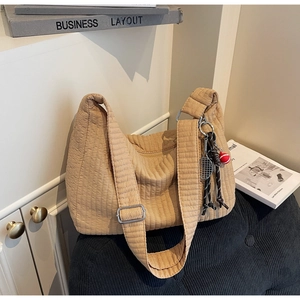 Détail du sac bandoulière matelassé beige avec breloque raquette et large bandoulière