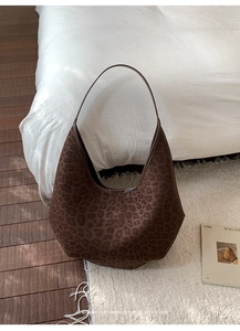 Close-up of leopard print hobo bag on white rug with a modern vintage aesthetic