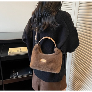 Detail of plush brown teddy handbag with leather handle and adjustable shoulder strap