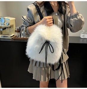 Close-up of white plush faux fur bucket bag with black drawstring and wide leather strap