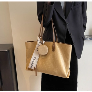 Macro detail of khaki quilted tote bag with brown leather handles and heart-printed scarf
