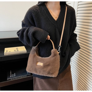 Close-up of brown faux fur handbag with golden metal plate and adjustable strap