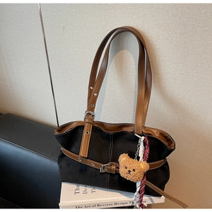Détail du sac fourre-tout en daim vintage avec lanière en cuir et pendentif ours