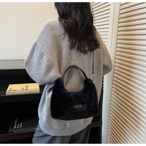 Close-up of black faux fur shoulder bag with adjustable strap and minimalist logo patch