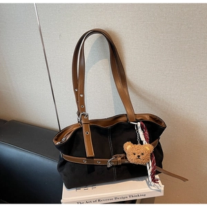 Détail du sac cabas en daim vintage avec bordure en cuir et breloque ours décorative