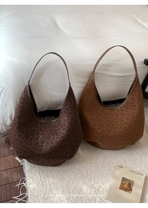 Two leopard print suede tote bags in dark brown and caramel displayed in a lifestyle setting