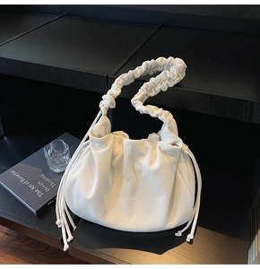 Nahaufnahme der weißen Cord-Tasche mit gerafftem Griff und Kordelzug-Quasten-Detail