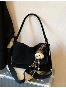 Fashionable black canvas crossbody bag with adjustable strap and bear pendant