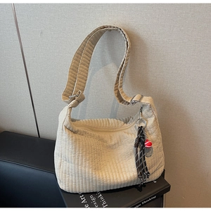 Détail du sac hobo matelassé kaki clair avec texture ondulée et breloque tennis