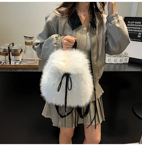 Detail of white plush backpack featuring black drawstring closure and fluffy texture