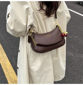 Detail of dark brown lychee leather underarm bag with gold chain and cherry charm