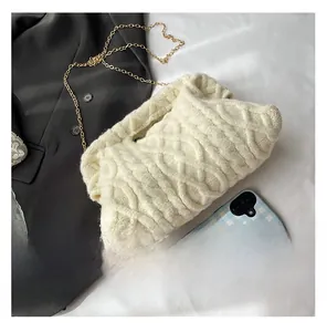 Detail of off-white cable knit makeup bag with soft texture and golden chain strap