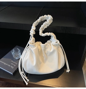 Detailansicht der cremefarbenen Cord-Struktur und des Faltenriemens der Cloud-Tasche