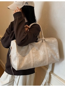 Grand sac de voyage en cuir tressé crème avec bandoulière porté par un mannequin