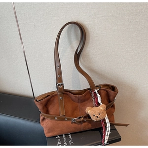 Gros plan d'un sac cabas vintage en daim marron avec sangles et breloque ourson
