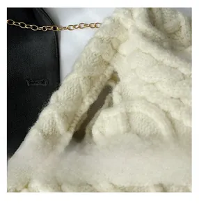 Detailed macro view of the cream quilted knit texture with a decorative gold chain strap
