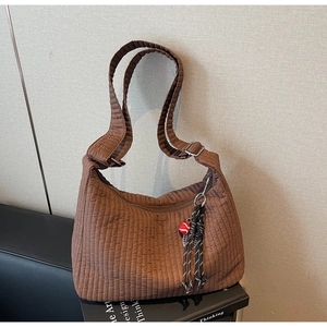 Détail du sac hobo marron à texture plissée avec un pendentif créatif de boule rouge