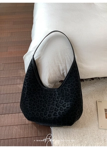 Detail of minimalist black leopard print hobo bag with velvety texture on white bedding
