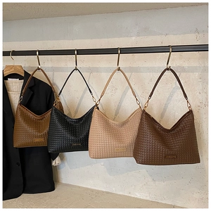 Detail of woven hobo bags in caramel, black, beige and dark coffee with metal logo