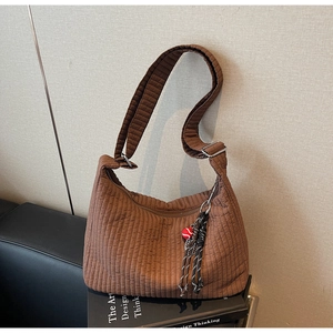 Détail d'un sac hobo matelassé marron foncé avec pompon frangé sur support de livre