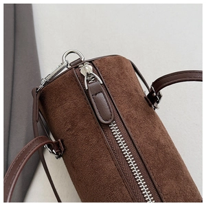 Close-up of brown cylindrical handbag showing suede texture and silver hardware